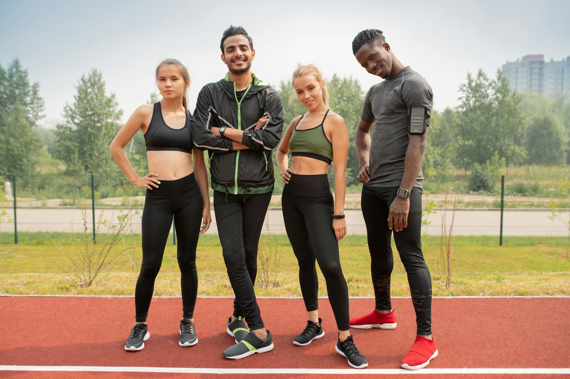 Row of happy young intercultural friends in activewear looking at you